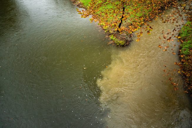 Two streams connect: one of which is light brown due to sediment runoff.