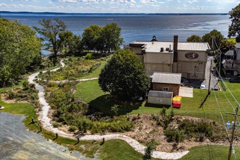 A white trail weaves around a museum to the water.