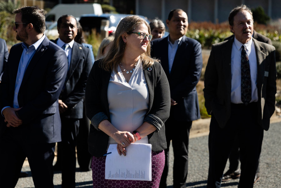 Julie stands in front of a group of men wearing suits.