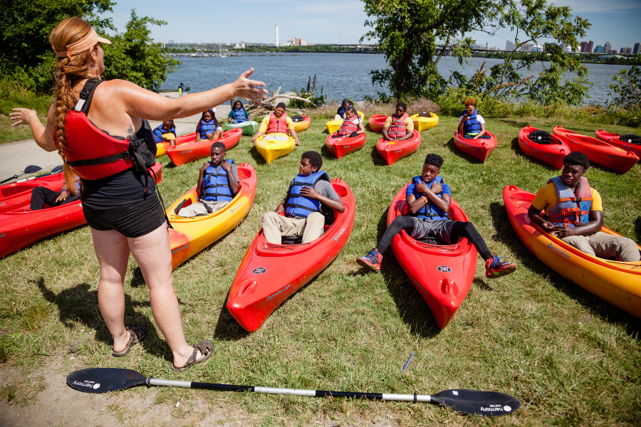 Woman instructs kids on how to kayak before getting out onto the water.